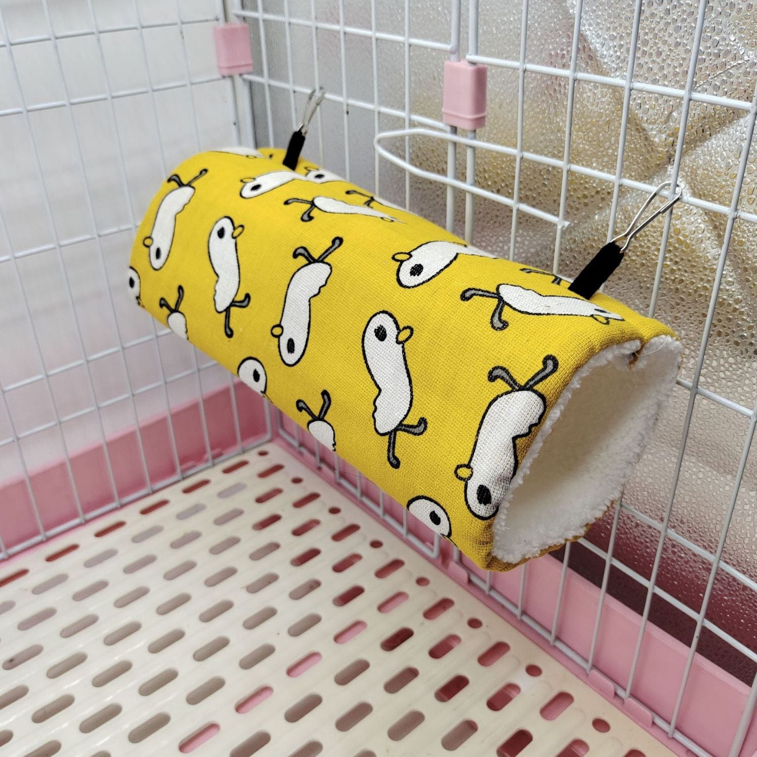 Cozy Critter Tunnel in gele stof met witte diertjes opgehangen in kooi